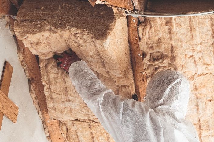 Ein Handwerker in Schutzkleidung bringt Dämmmaterial an, um das Dach von innen zu dämmen.